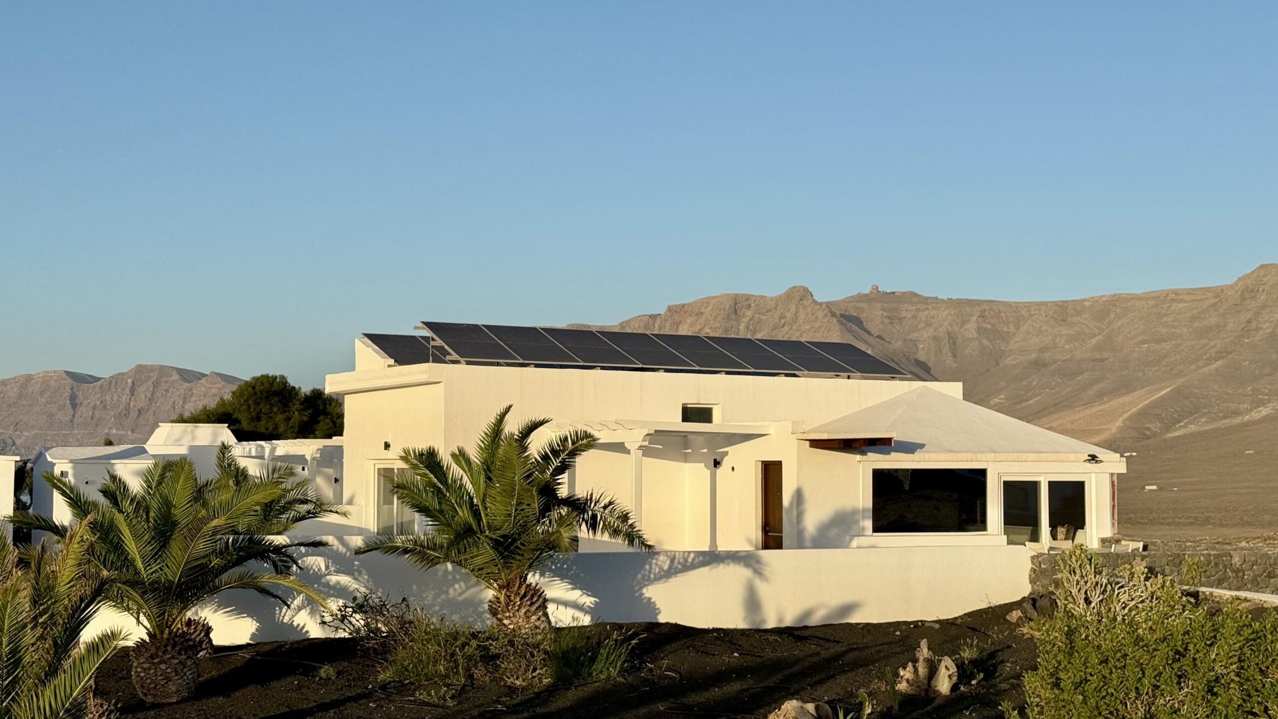 La villa con placas solares en el tejado y el risco al fondo