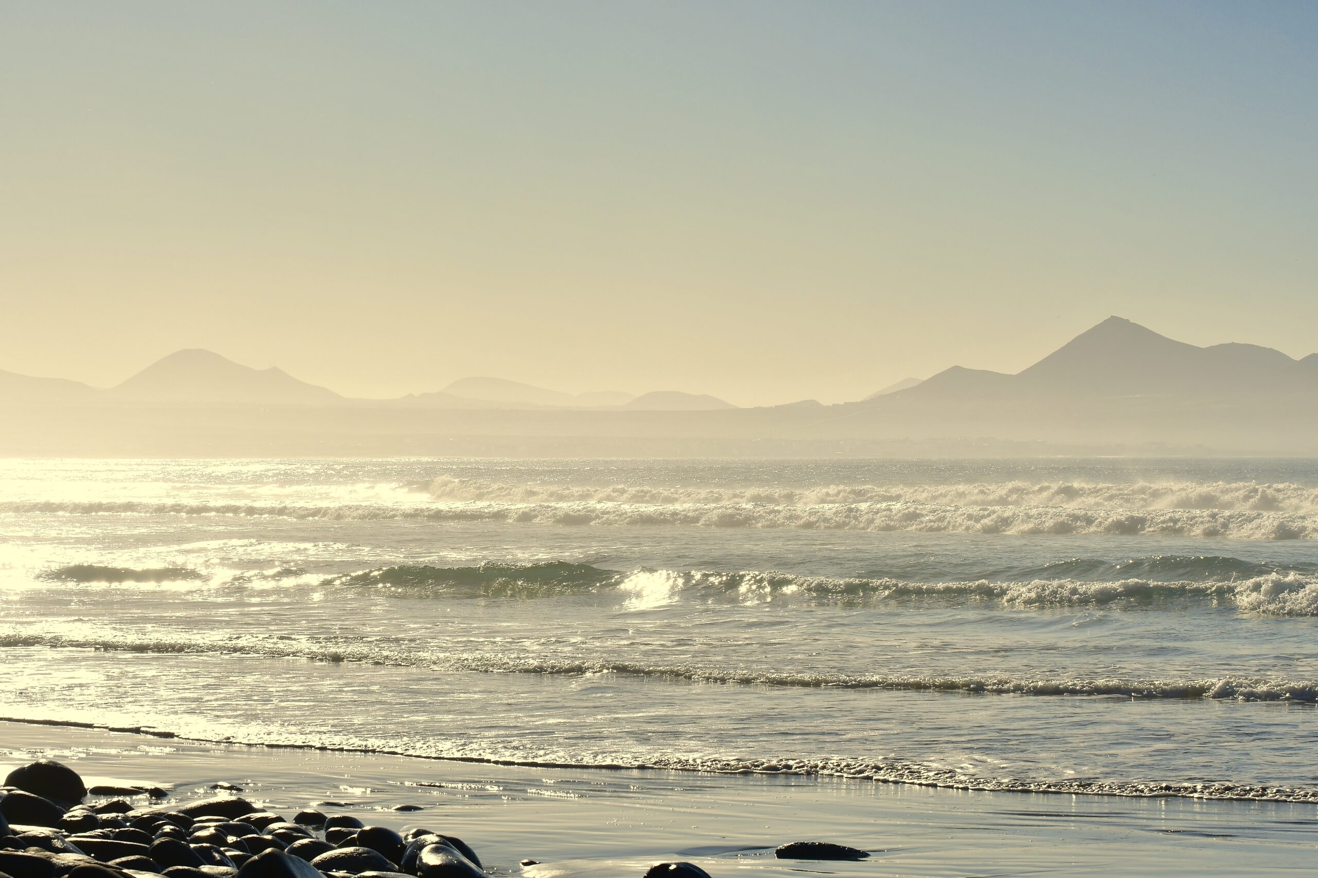 Der Strand von Famara im goldenen Licht mit den Bergen im Hintergrund